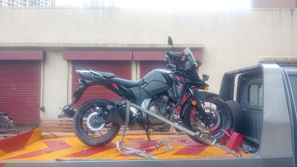 Adventure motorcycle secured and strapped down on a flatbed tow truck, ready for safe transport