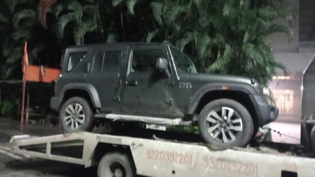 Dark Mahindra Thar SUV loaded onto a tow truck late at night, showing 24-hour service availability.